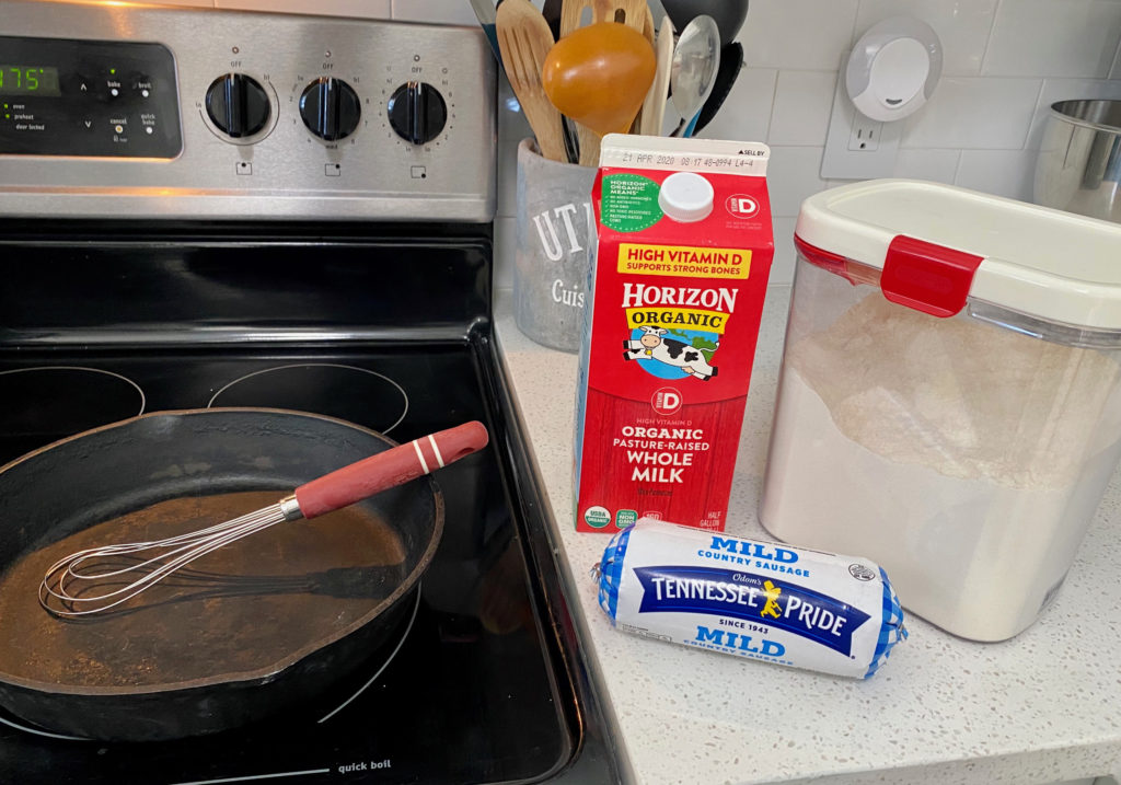 A cast iron skillet on the stove with a carton of milk and package of sausage on the counter, the ingredients for biscuits and gravy. [Biscuits and Gravy]