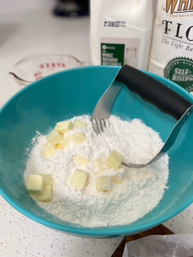 Flour and butter with a pastry cutter in a mixing bowl. [buttermilk biscuits]