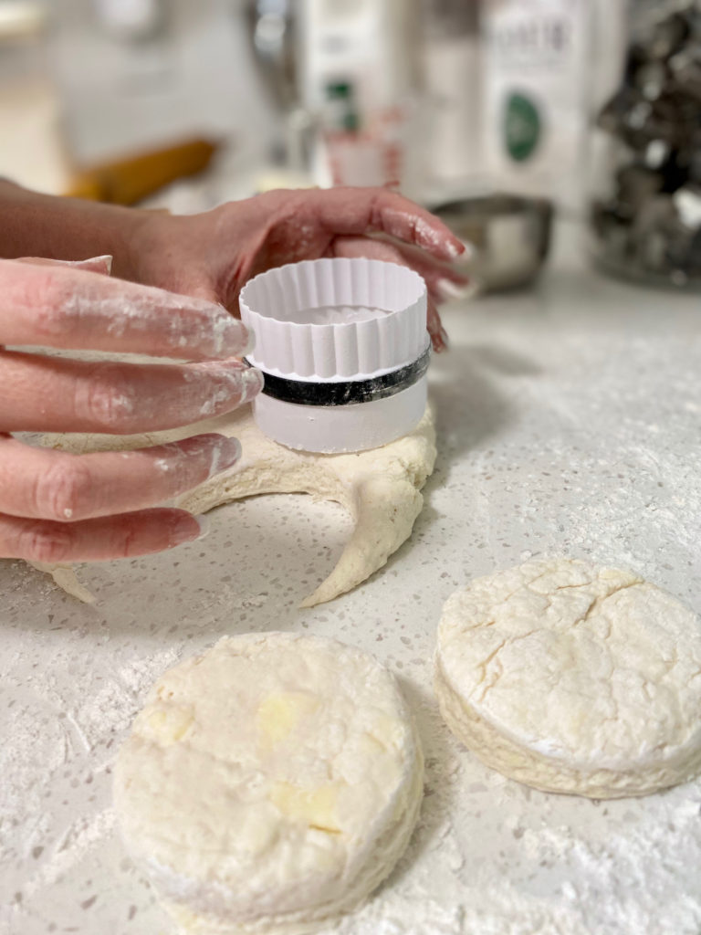 Cutting out biscuit dough on a floured counter. [buttermilk biscuits]