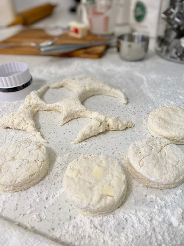 Cut out biscuit dough with dough scraps on a floured counter. [buttermilk biscuits]