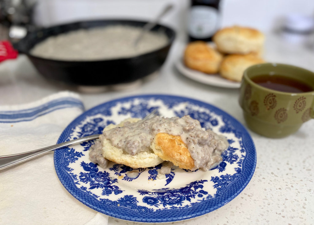 Sausage gravy and biscuits on a blue and white plate.