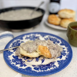 Sausage gravy and biscuits on a blue and white plate.