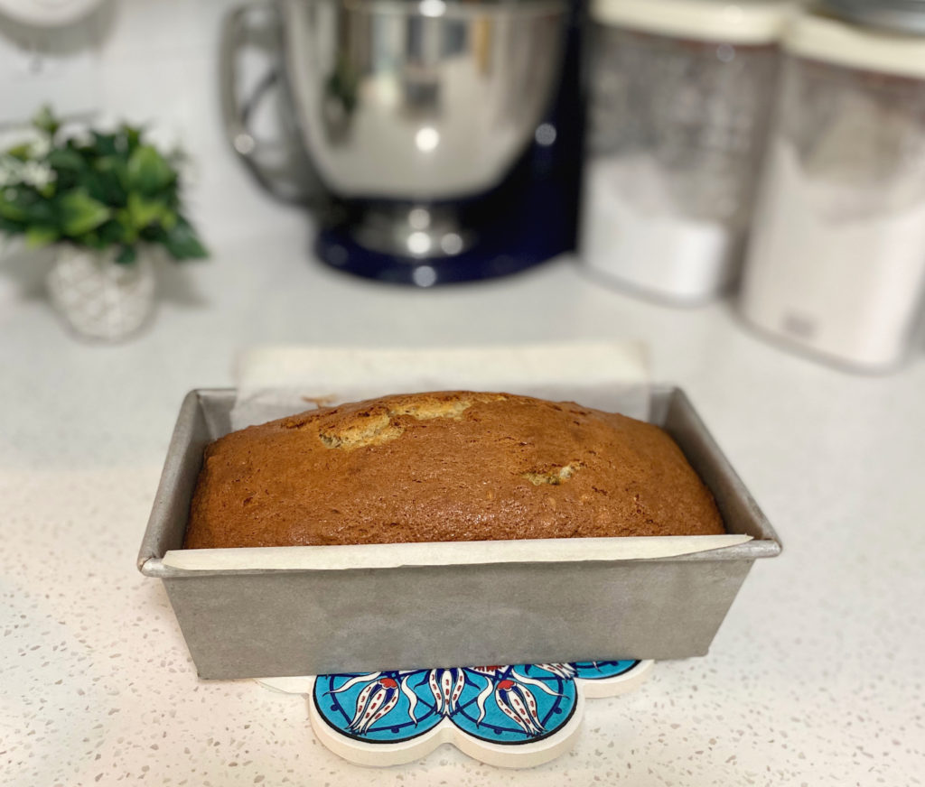 Golden baked banana bread in a loaf pan cooling on the counter. [decadent banana bread]