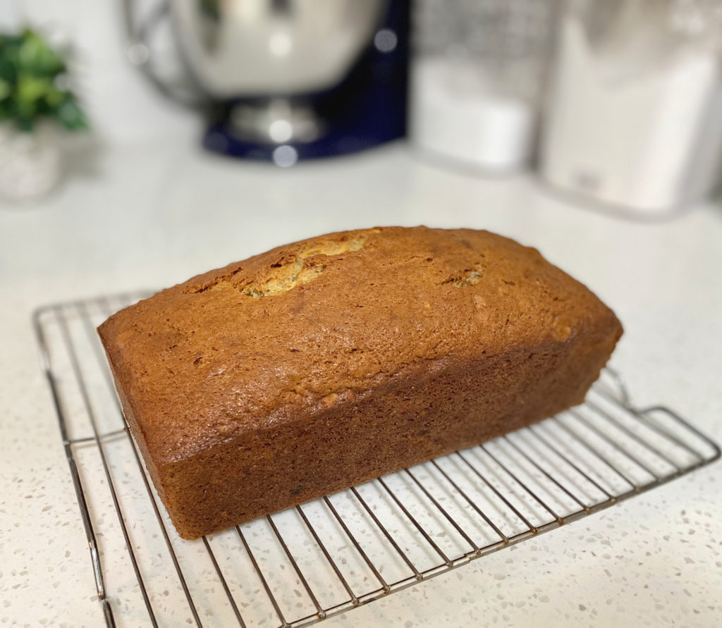 A loaf of Decadent Banana Bread sitting on a cooling rack. [decadent banana bread]