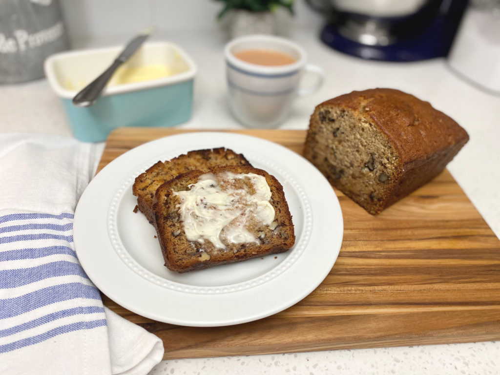 A piece of toasted bread on a plate with butter. [decadent banana bread]