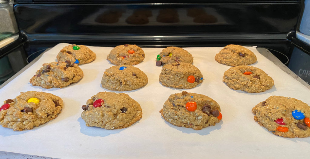 Baked cookies lined up on a baking sheet with parchment paper [Monster Cookies]