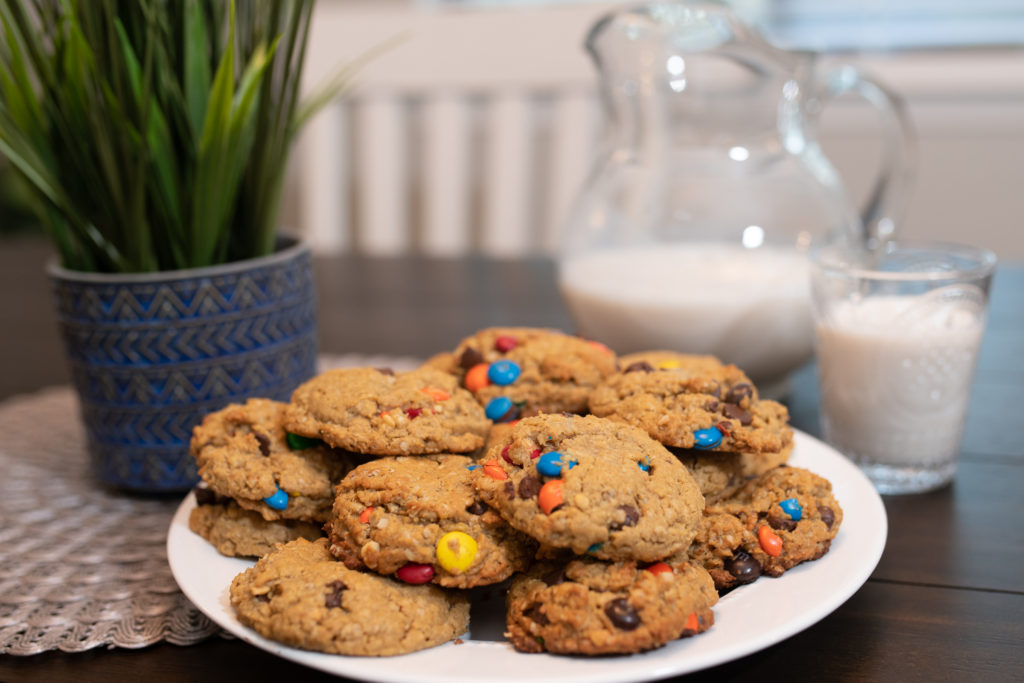 A stack of cookies on a plate with a glass of milk [Monster Cookies]