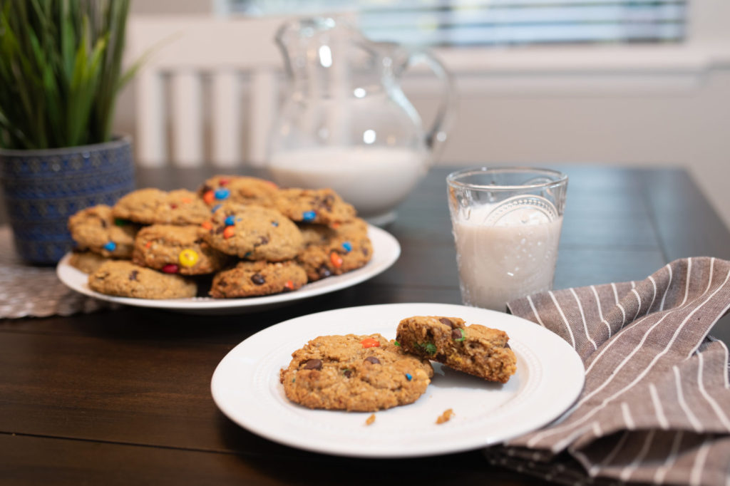 Two monster cookies on a plate with a glass of milk. [monster cookies]