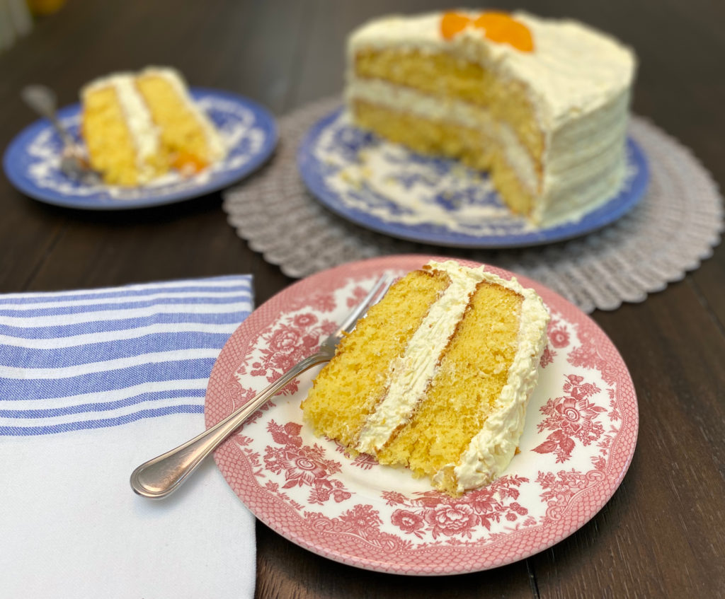 A slice of cake on a red plate with the whole cake in the background. [pea picking cake]