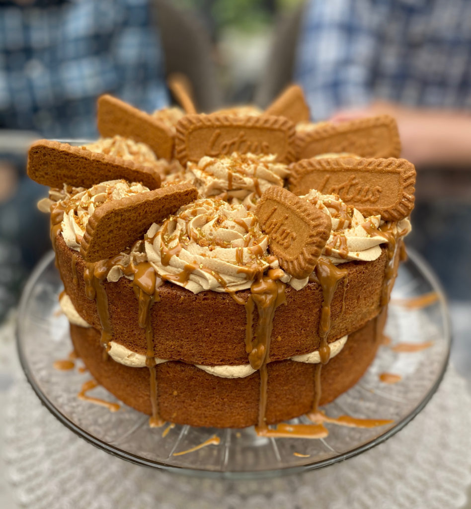 Full view of biscoff cake on a glass cake plate. [biscoff cake]