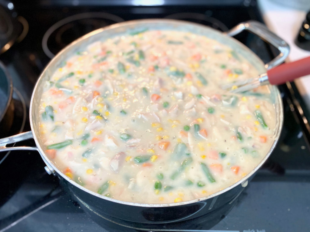 A pan of chicken pot pie filling cooking on the stove. [Classic Chicken Pot Pie]