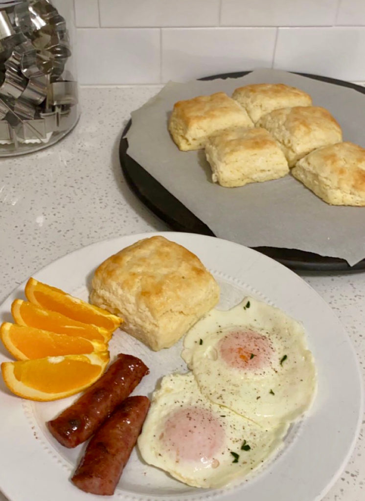 Square buttermilk biscuits on a plate with eggs, sausage, and orange slices. [buttermilk biscuits]