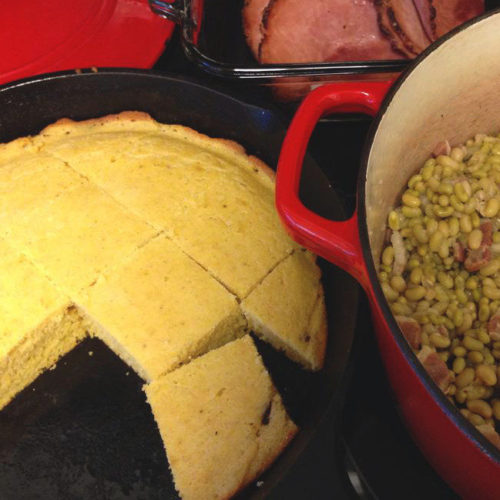 A skillet of southern cornbread with a pot of beans next to it.