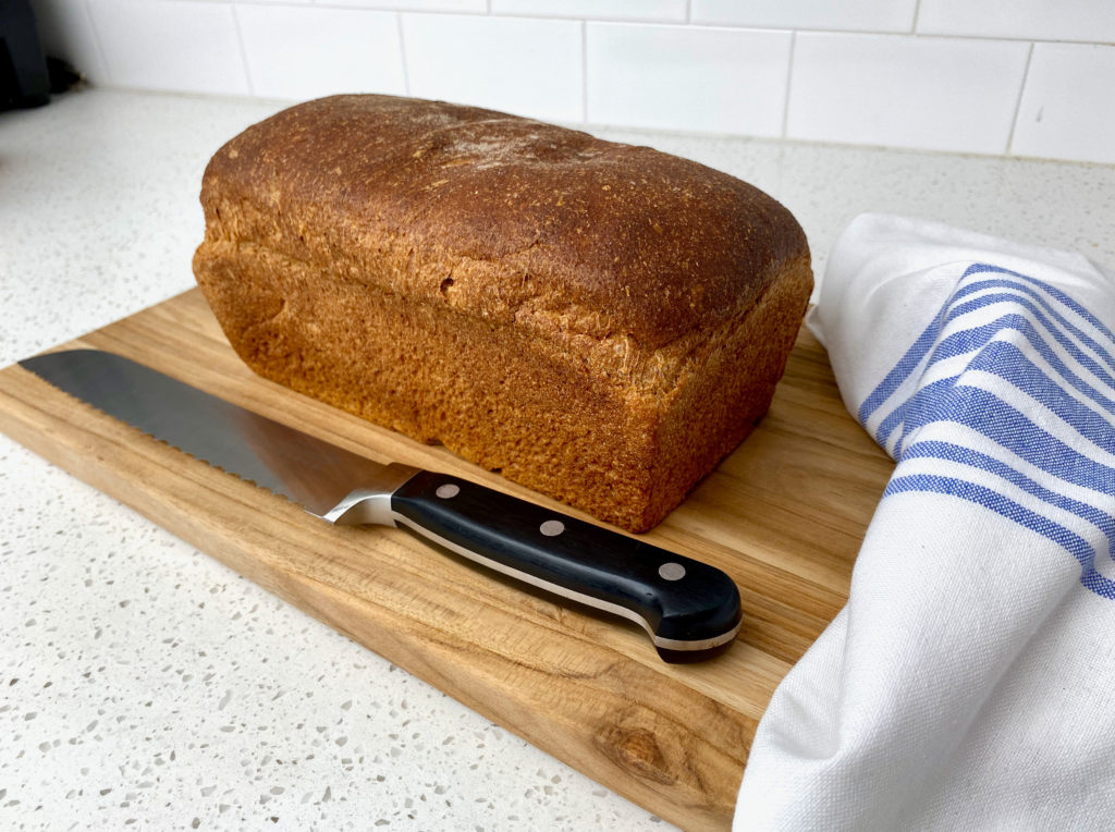 An unsliced loaf of honey whole wheat bread