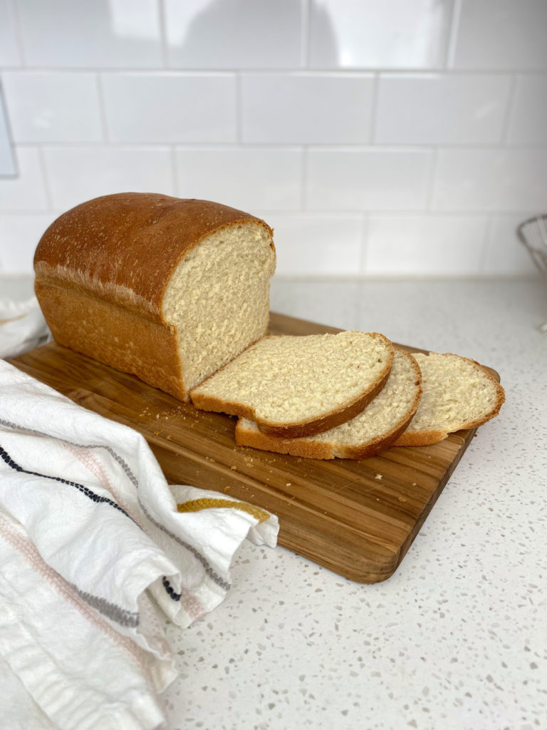 A fresh-baked loaf of Buttermilk Bread on a cutting board, sliced. 