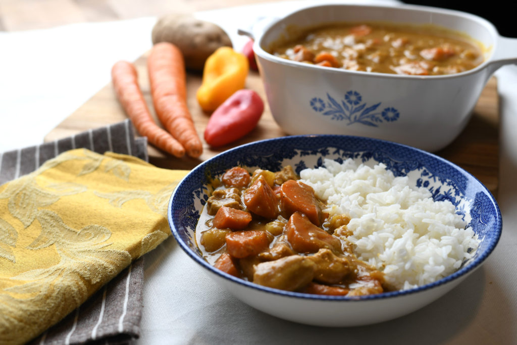 A bowl of Japanese Curry with rice, and ingredients in the background